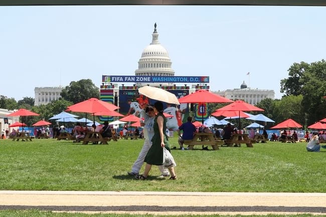 As a heat wave envelops the nation, attendees at the Great American State Fair in Washington, D.C. find shade under large umbrellas at the FIFA Fan Zone on the National Mall on June 30, 2026. (Photo by Sam Gauntt/States Newsroom)