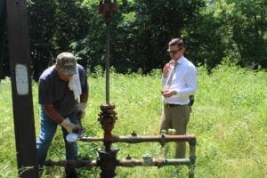 Marietta Bob Wilson, an oil producer in Washington County (left) reads the pressure of an injection well in Marietta while Ohio state Rep. Tristan Rader, D-Lakewood watches. (Photo by Megan Henry, Ohio Capital Journal).