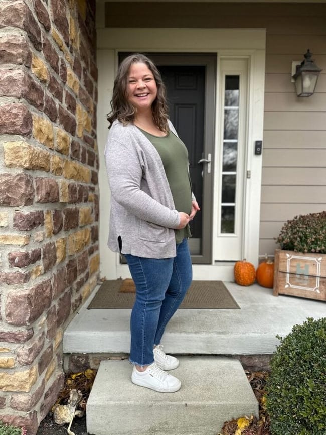 Sarah Hanline stands on a step holding her pregnant belly.