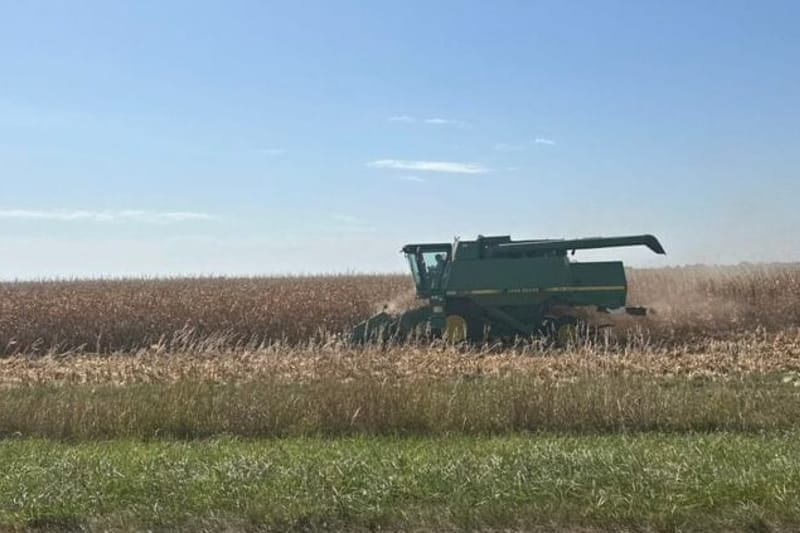 A farmer harvests corn beside a highway. (Photo by Cami Koons/States Newsroom.)