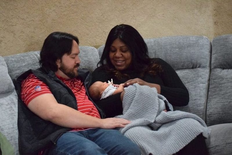 A couple sits with their newborn inside their Bentonville, Arkansas, home earlier this month. Nearly a quarter of pregnant women aren’t getting prenatal care in the early stages of pregnancy, according to a new analysis from the U.S. Centers for Disease Control and Prevention. (Photo by Antoinette Grajeda/Arkansas Advocate)