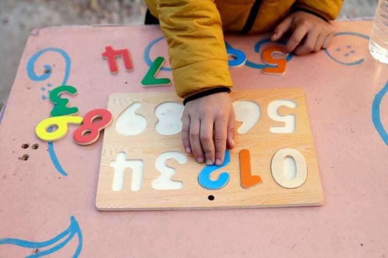 A boy plays with a wooden numbers puzzle. (Getty Images)