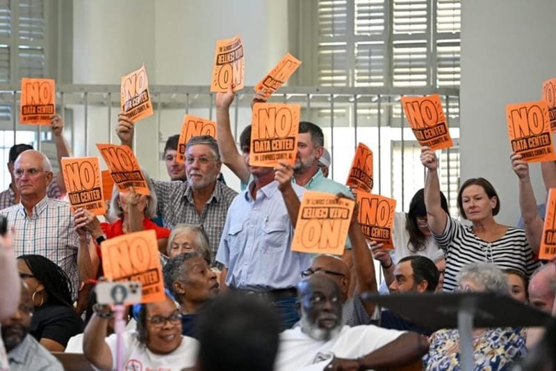 Alabamans hold up signs that read “No Data Center” at a County Commission meeting on Aug. 24, 2026, in Hayneville, Alabama, in the Lowndes County Courthouse. (Anna Barrett/Alabama Reflector)