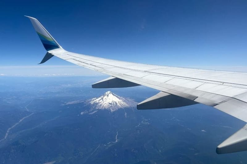 A plane flies above Oregon's Mount Hood on a recent morning. Rising fuel costs for cars and airplanes are adding extra strain to abortion funds that help people pay to travel for care in other states. (Photo by Julia Shumway/Oregon Capital Chronicle)