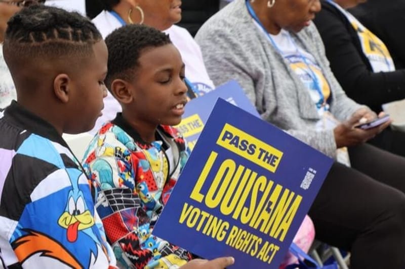 Jericho Morris and Christian Morris Jr. join their mom, Pamela Evans of Shreveport, and hundreds of others in a voting rights rally at the Louisiana State Capitol in Baton Rouge on March 18, 2026. Democratic state lawmakers proposed a Louisiana voting rights law earlier this year aimed at strengthening protections against gerrymandering and voter suppression. It later died in committee. (Photo by Wes Muller/Louisiana Illuminator)