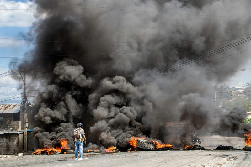 A reporter records video near a burning barricade during a protest in Haiti. (Photo: Carlin Trezil/Unsplash)