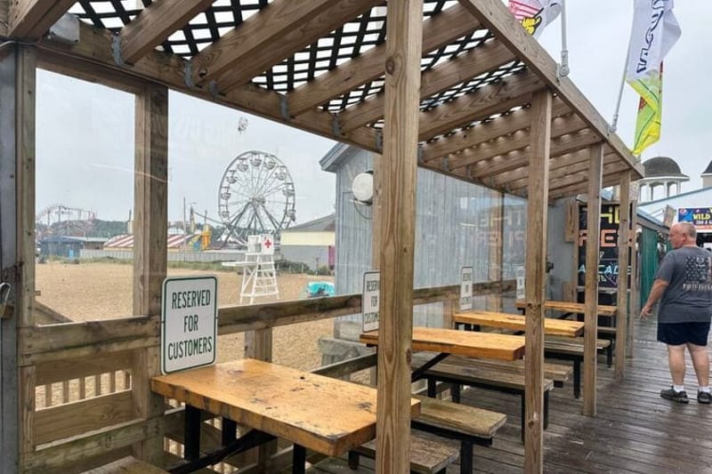 Empty tables line the pier at Old Orchard Beach, Maine, where a drop in Canadian visitors has affected business. Nationally, leisure and hospitality jobs dipped 61,000 in June, reflecting slower seasonal hiring. (Photo by Kevin Hardy/Stateline)